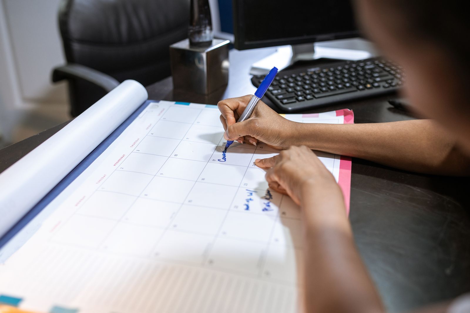 Close-up of a person planning a schedule on a desk calendar