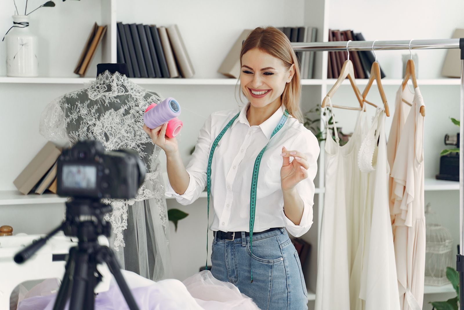 Smiling small business owner recording a video tutorial with a camera in her workshop studio.