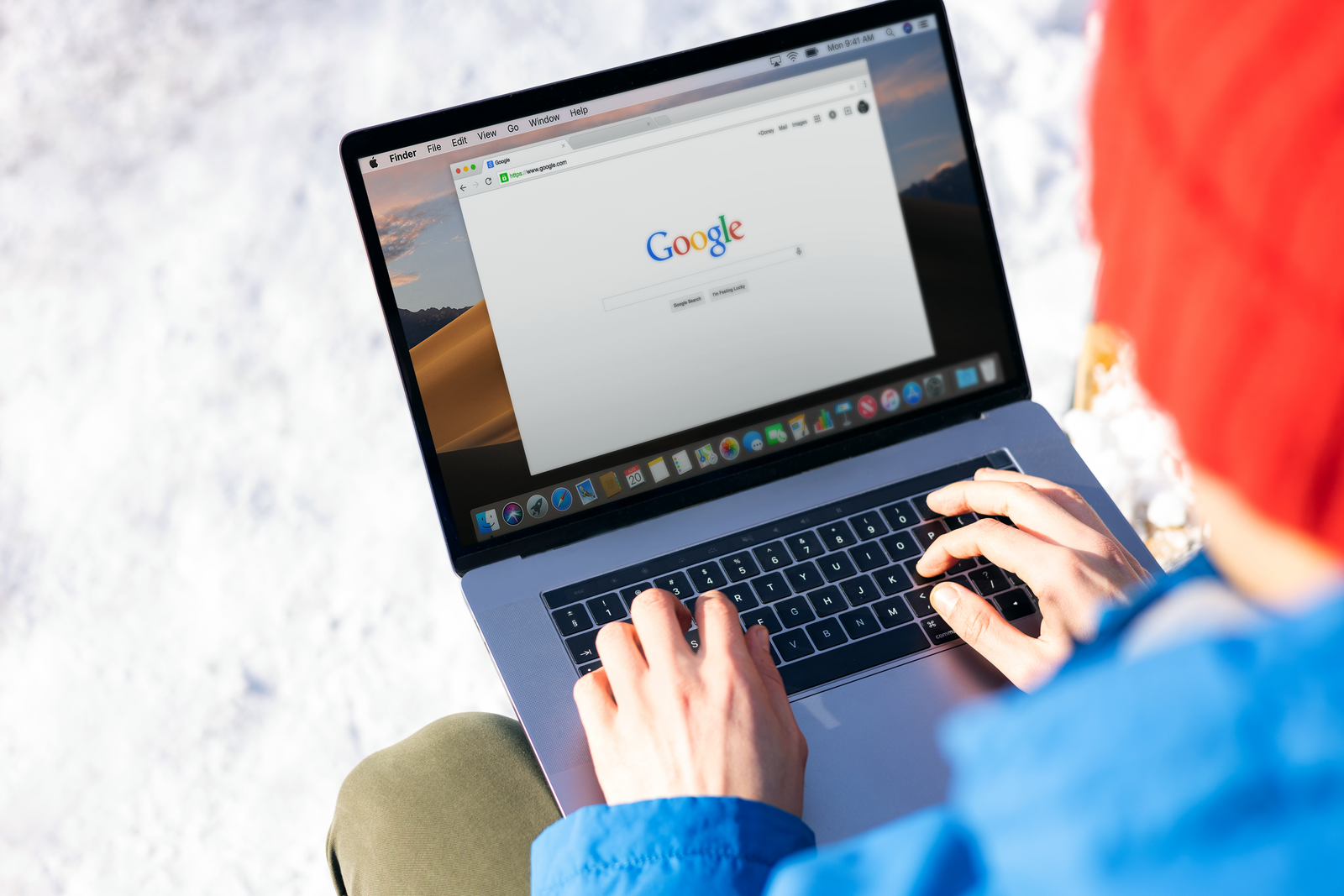 Person typing a search query into Google on a laptop at a desk.