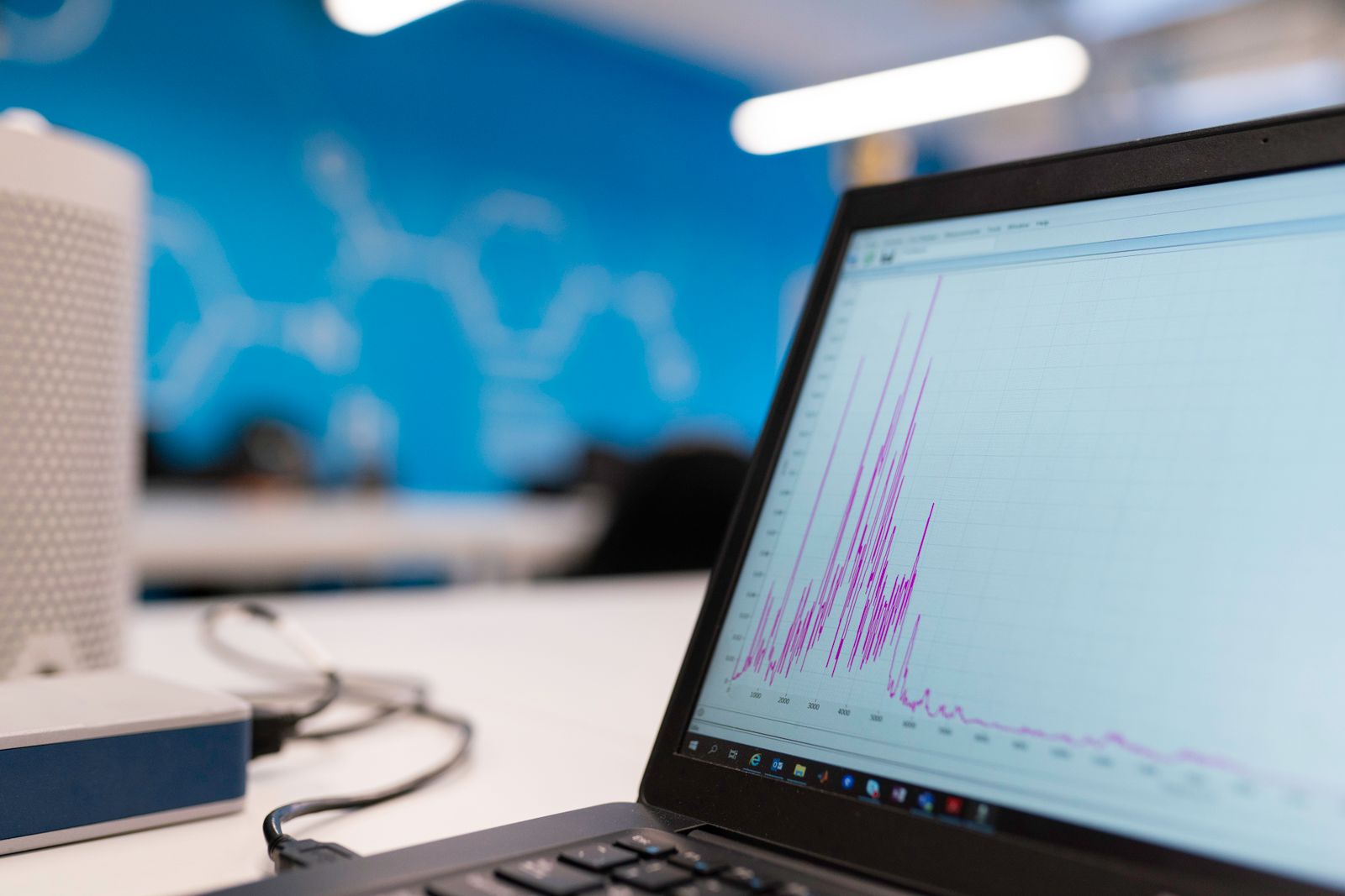 A laptop screen displaying a line graph of performance data on a desk in a modern office.