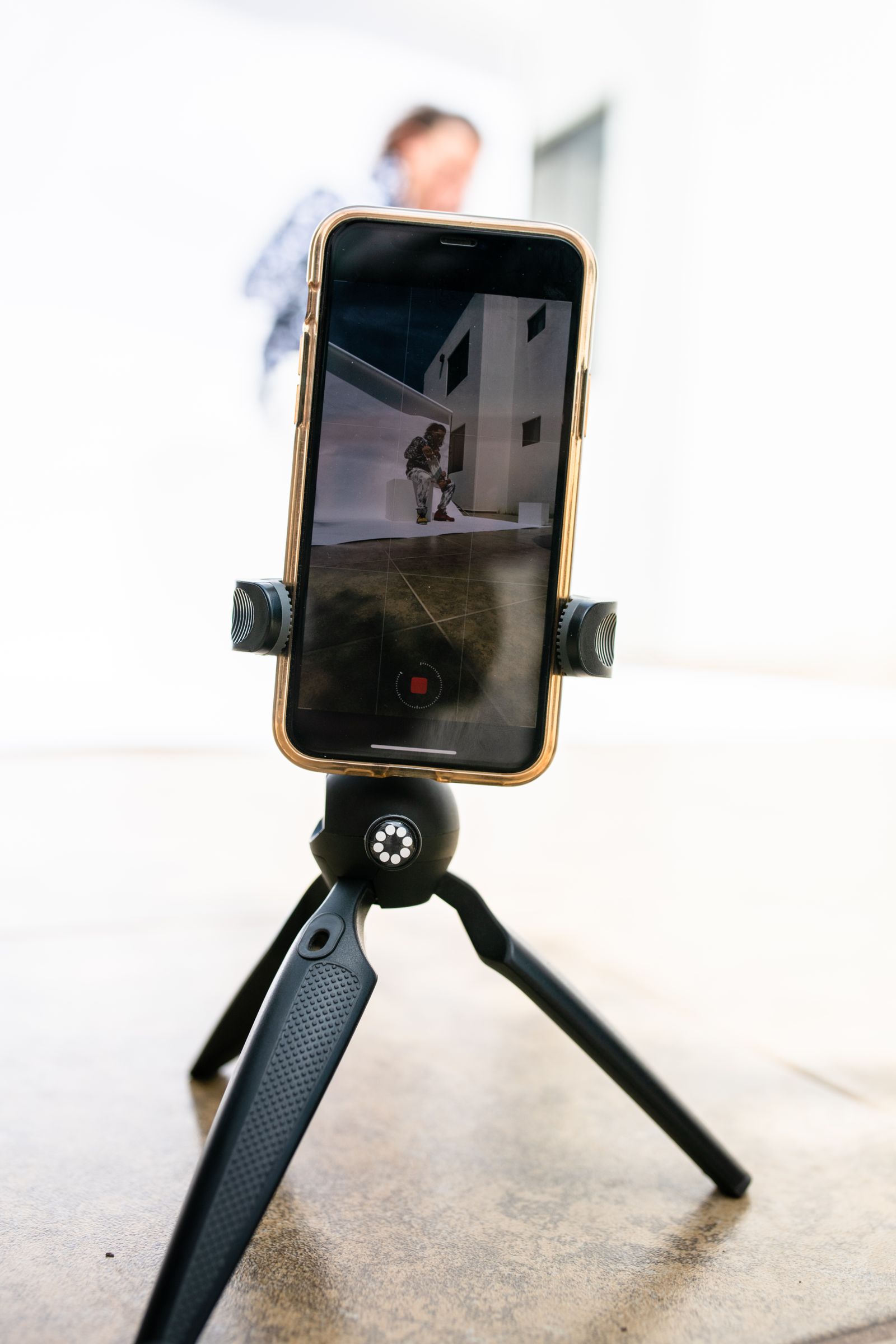 A smartphone mounted on a small tripod recording video indoors.