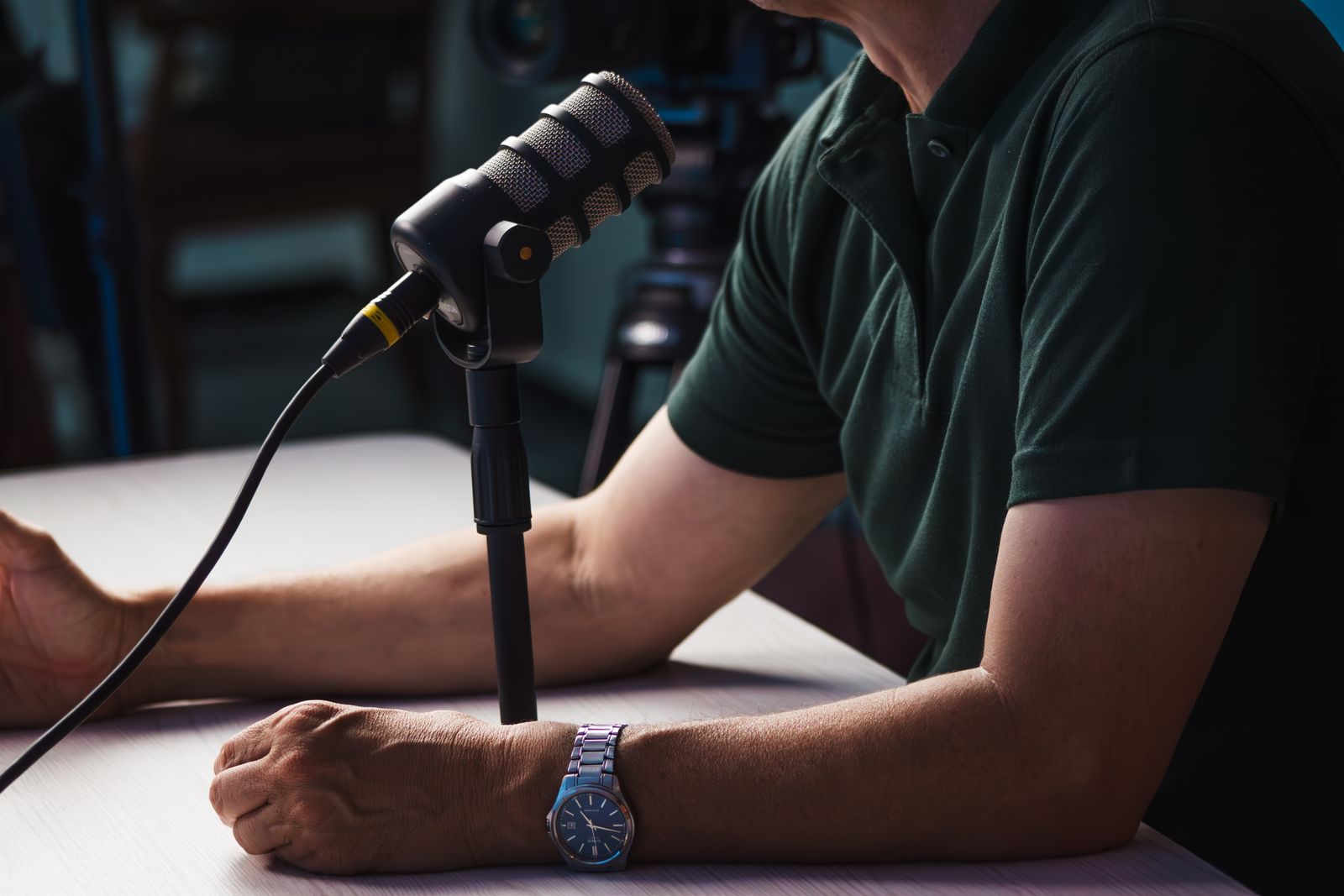 Close-up of a podcast microphone and professional audio equipment on a desk in a dimly lit studio.