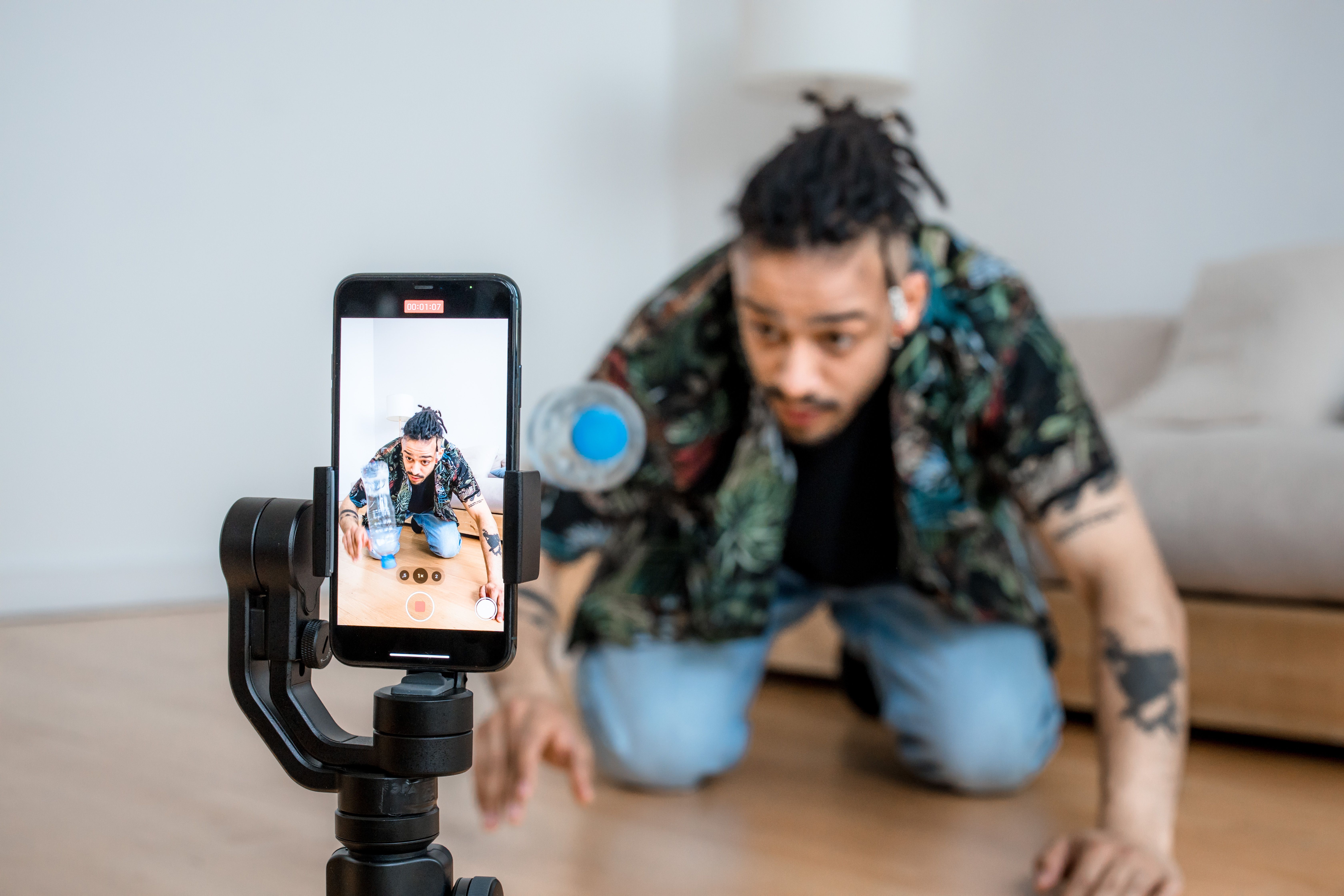 Content creator filming vertical video with a smartphone on a gimbal indoors.
