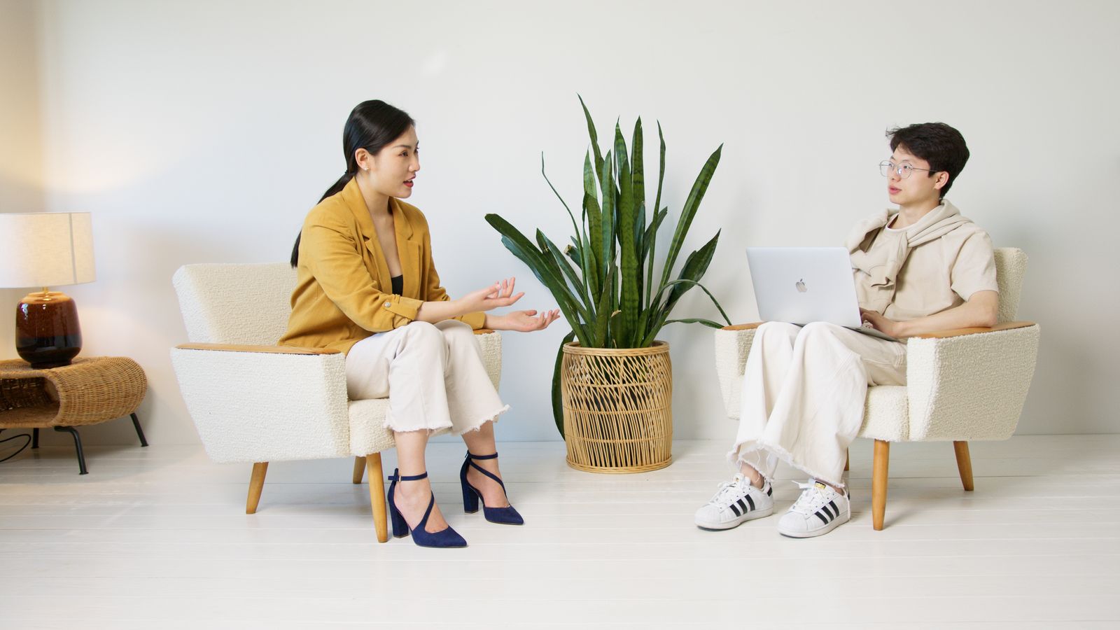 Two people sitting in armchairs having a relaxed interview conversation in a bright minimalist room.