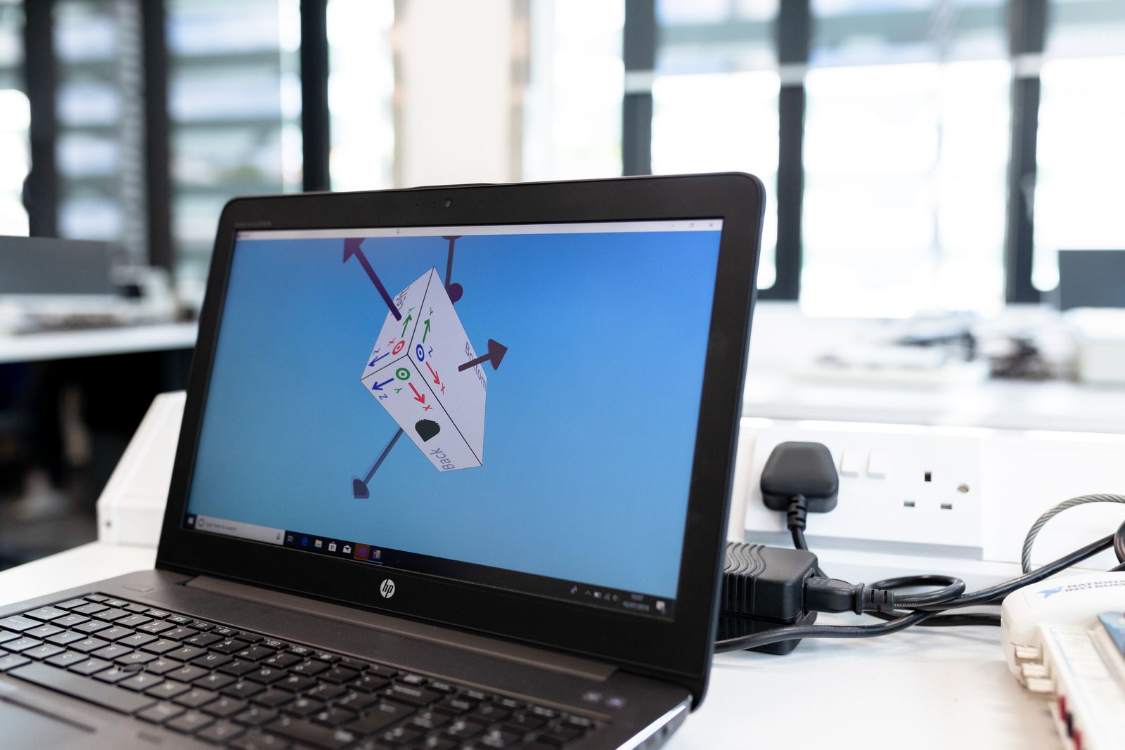 A laptop on an office desk displaying design software with a project open on screen.