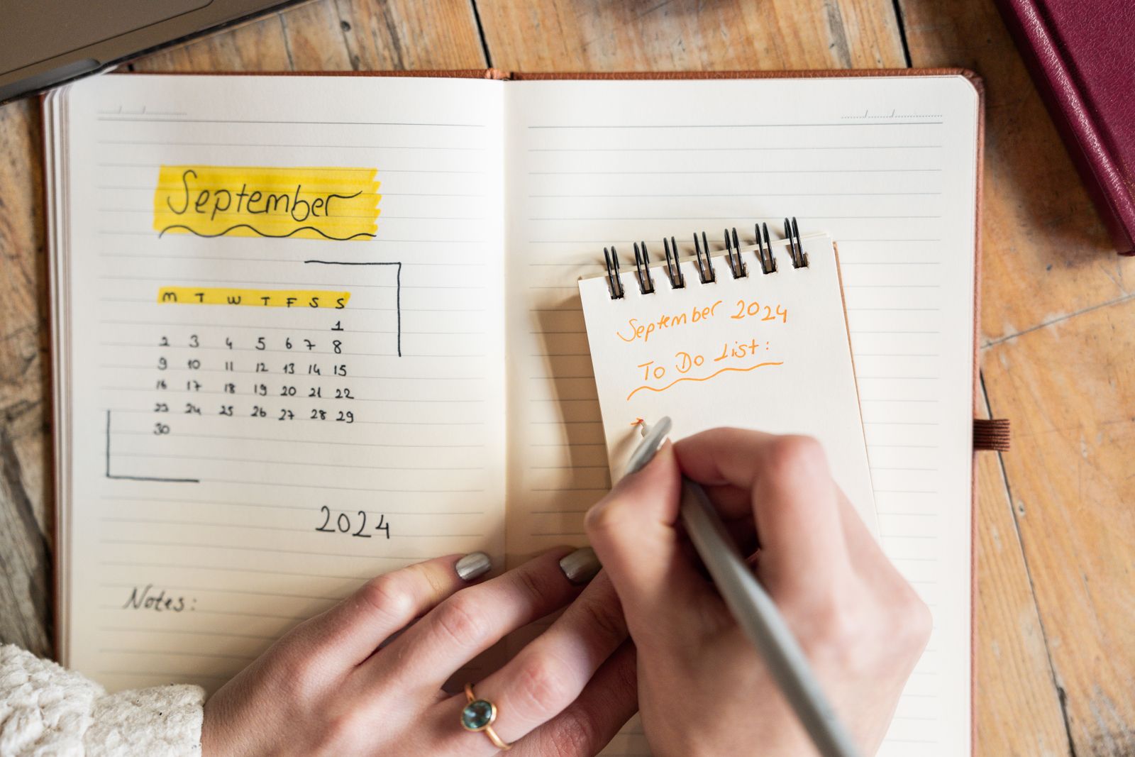 A close-up of a person writing a short to-do list by hand in a notebook.